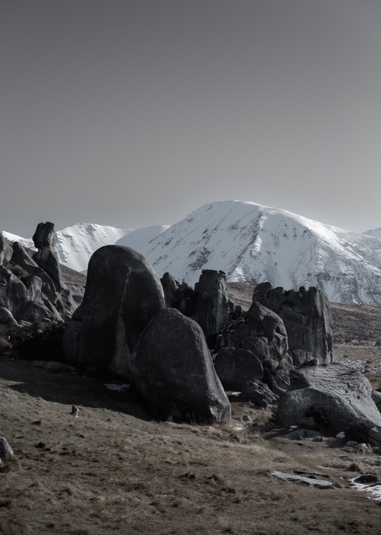 Dark boulders beneath a snow-covered mountain